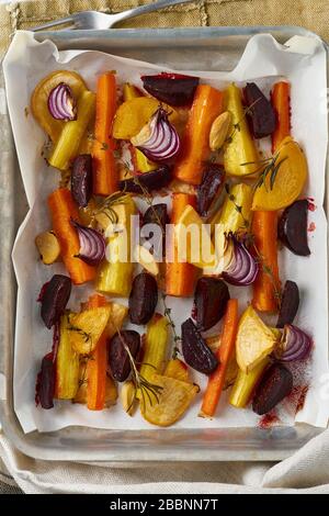 Verdure arrostite colorate su vassoio con pergamena. Mix di carote, barbabietole, rape Foto Stock