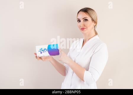 Ritratto del contenuto giovane cosmetologo femminile in camice da laboratorio che consiglia il prodotto di riempimento su sfondo isolato Foto Stock