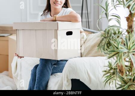 scatola di cartone con oggetti personali nelle mani di una giovane donna Foto Stock