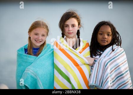 Ritratto di tre ragazze che si levano in piedi su un molo che porta asciugamani. Foto Stock