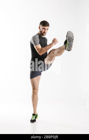 Immagine dell'atletico caucasico nello sportswear calci mentre si lavora isolato su sfondo bianco Foto Stock