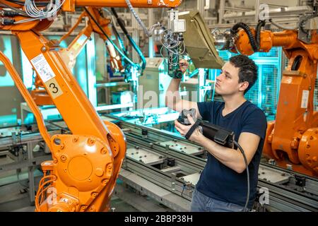 programmazione di bracci robot per un nuovo prodotto da parte di un ingegnere di produzione Foto Stock