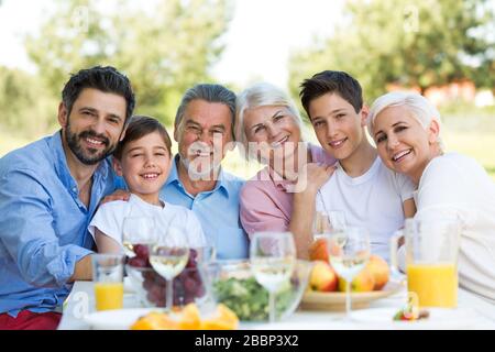 Famiglia seduta a pranzo in giardino Foto Stock