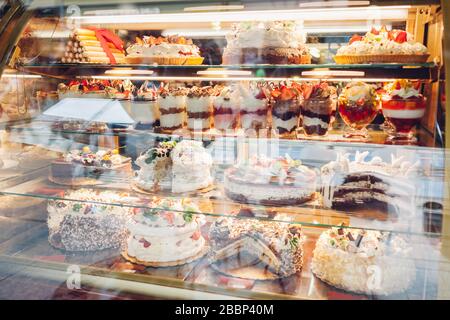 Assortimento di dessert sulla vetrina dei caffè. Varietà di torte tiramisù torte con diversi sapori frutta in negozio. Foto Stock