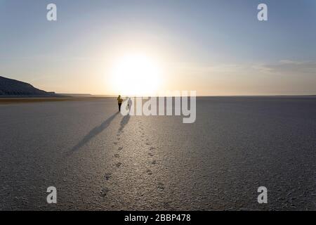 Madre e figlio camminano nel vuoto paesaggio drammatico, taces piede di lievito a lago salato di Tuzbair, Aktau, Mangystau, Kazakhstan, Foto Stock