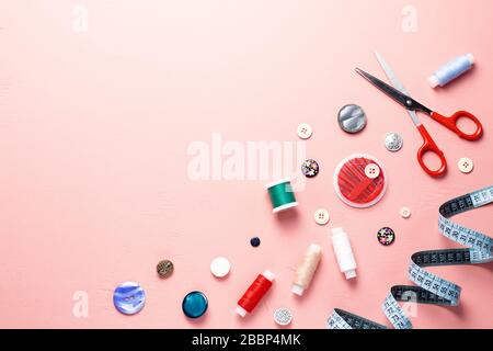 Disposizione di utensili per cucire e accessori su sfondo rosa, vista dall'alto Foto Stock