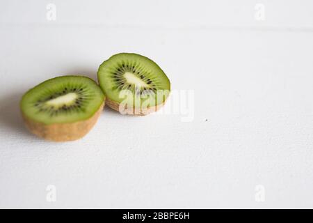 Affettato a metà, fresco, kiwi frutta su un tavolo bianco pronto per uno spuntino. Foto Stock