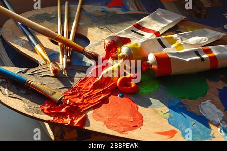 Pennelli, palette d'artista, dipinti ad olio su scrivania in studio pittore. Primo piano. Foto Stock