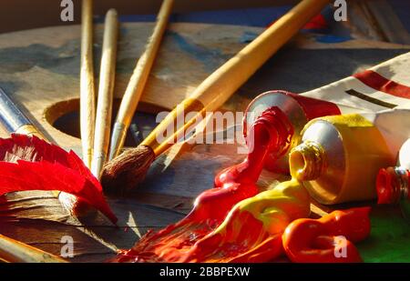 Pennelli, palette d'artista, dipinti ad olio su scrivania in studio pittore. Primo piano. Foto Stock