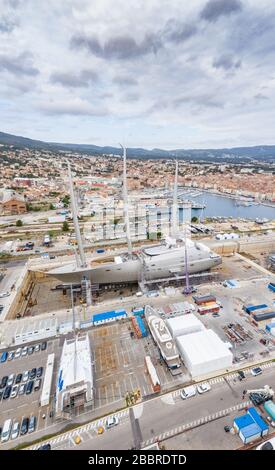 Veduta aerea della darsena a la Ciotat città, Francia, la gru di carico, barche in riparazione, una barca a vela di lusso e yacht a motore, la montagna è su Foto Stock