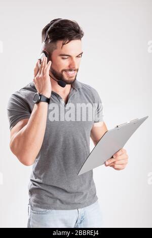 Sorridente giovane addetto alla consegna che tiene e tiene un portadocumenti Foto Stock