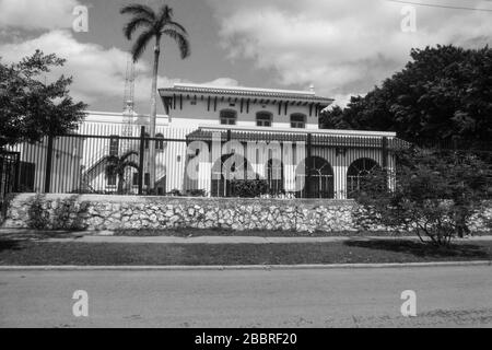 L'ambasciata canadese Havana Cuba muro nubi nube vecchie pareti bianche muro palme bianche strada percorso muro pietra cancelli alti recinto nero cespugli di metallo Foto Stock