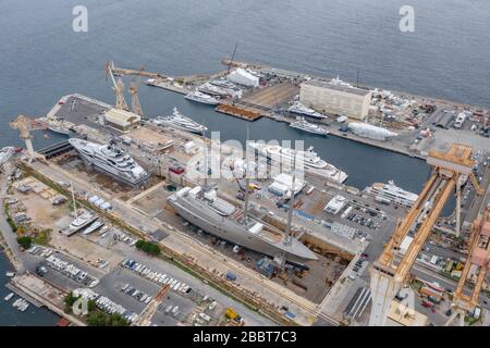 Veduta aerea della darsena a la Ciotat città, Francia, la gru di carico, barche in riparazione, una barca a vela di lusso e yacht a motore, la montagna è su Foto Stock