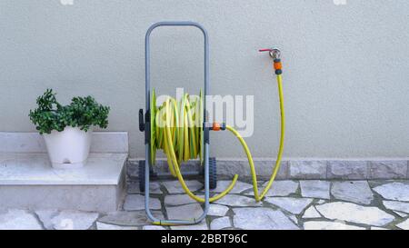 tubo da giardino per irrigazione vicino alla parete della casa Foto Stock