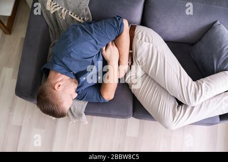 L uomo che soffre di mal di stomaco sdraiato sul divano Foto Stock