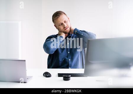 Giovane Imprenditore in ufficio presso il Desk che soffrono di dolore al collo Foto Stock