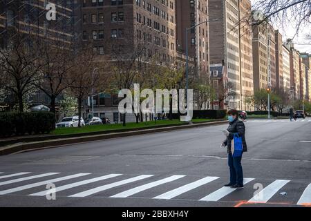 New York, Stati Uniti. 1st Apr, 2020. Le persone indossano maschere facciali mentre aspettano di attraversare una strada Park Avenue insolitamente vuota nella città di New York durante la crisi del coronavirus. Credit: Enrique Shore/Alamy Live News Foto Stock