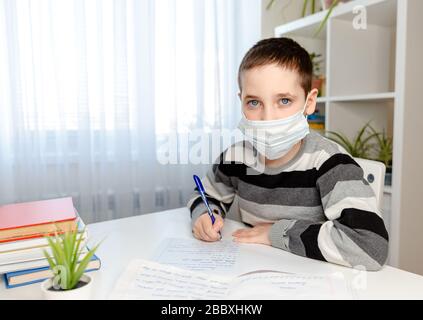 Malattia ragazzo in maschera medica studiare a casa e fare i compiti Foto Stock