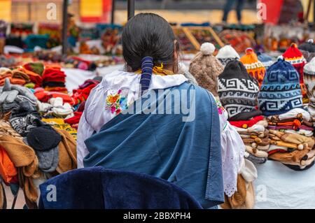 Donne indigene in abbigliamento tradizionale e acconciatura dal suo mercato stallo sulla domenica arte e artigianato mercato di Otavalo, a nord di Quito, Ecuador. Foto Stock