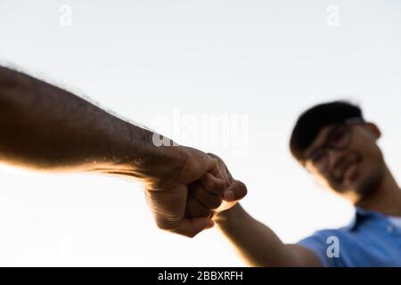 Chiudete due uomini che danno un colpo di pugno mostrando unità e lavoro di squadra. Amicizia felicità tempo libero partenariato concetto di squadra. Foto Stock