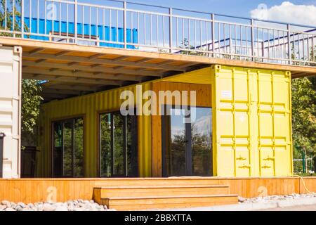 Almaty, Kazakhstan - 08 luglio 2019: Casa moderna di costruzione di metallo fatta dai contenitori gialli di spedizione sulla spiaggia e sfondo blu del cielo. Foto Stock