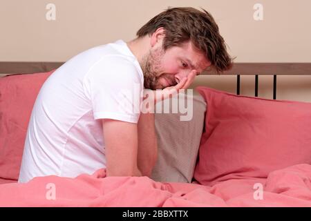 Giovane malato preoccupato seduto a letto a casa spaventoso e disperato sofferenza insonnia, depressione o crisi emotiva. Disturbo mentale, oressendo da solo co Foto Stock