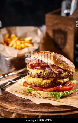 Succulento hamburger americano, hamburger o cheeseburger con due polpettine di manzo, con salsa e basato su sfondo nero. Concetto di fast food americano Foto Stock