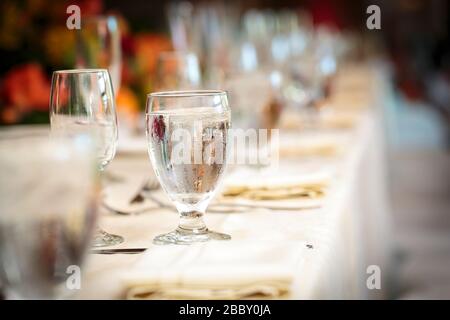 Tavolo da festa con tovaglia bianca e bicchieri pieni di acqua ghiacciata in un arredamento elegante Foto Stock