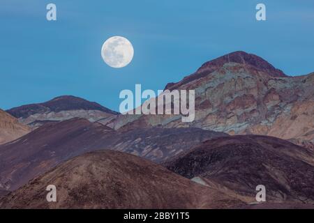 Luna piena che sorge su Artists palette, Death Valley National Park, California Foto Stock