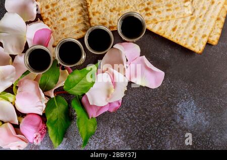 Matzoh passover festa ebraica festa matzoh con kiddush quattro tazza di vino rosso kosher su fiore rosa fresco Foto Stock