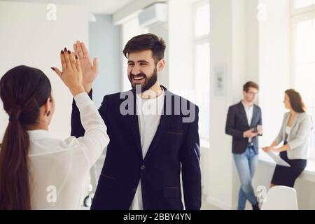 I lavoratori degli uomini d'affari danno una mano felice sorridente riuscito progetto sul posto di lavoro nell'ufficio moderno Foto Stock