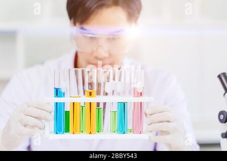 Lo scienziato o il medico osservano il test di reazione chimica molti campioni nella provetta. Lavorando con il test di formula della medicina in laboratorio medico Foto Stock