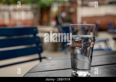 Bicchiere d'acqua pieno seduto su un tavolo da picnic in legno nel ristorante Foto Stock