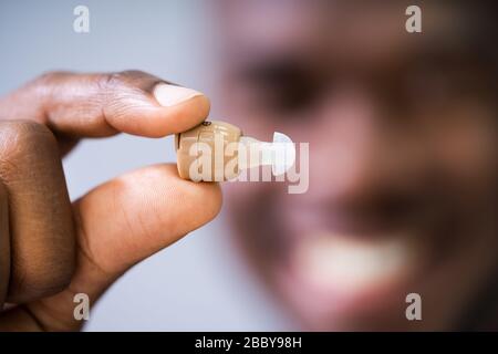 Close-up di un uomo felice Azienda Hearing Aid Foto Stock