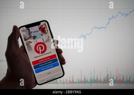 App Pinterest al telefono con cartellone finanziario bianco con prezzo crescente positivo in background Foto Stock