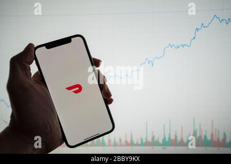 Doordash app al telefono con white Financial stock grafico con prezzo crescente positivo in background Foto Stock