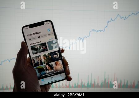App Apple TV al telefono con cartellone finanziario bianco con un prezzo crescente in background positivo Foto Stock