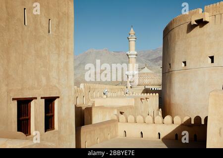 Vista tra torri di guardia del forte storico alla moschea. Nizwa, Sultanato dell'Oman. Foto Stock