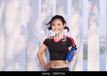 Scatto di bella runner femmina che tiene bottiglia d'acqua. Donna fitness prendere una pausa dopo l'allenamento all'aperto. Foto Stock