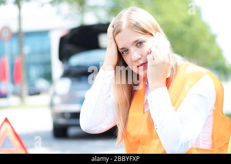 Una giovane donna si rompe con la sua auto Foto Stock