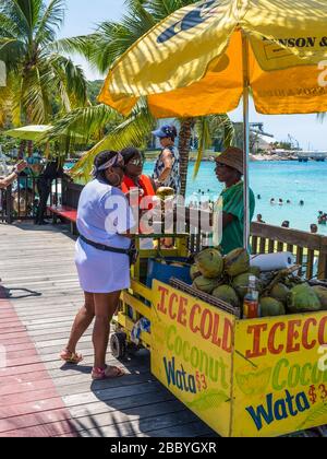 Ocho Rios, Giamaica - 22 aprile 2019: Il venditore di cocco è ricevuto il pagamento vicino al Fisherman's Beach a Ocho Rios, Giamaica. Foto Stock