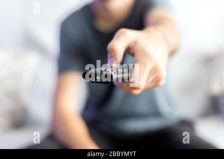 Un uomo seduto su un divano cambia il canale con un telecomando. Fuoco selettivo Foto Stock