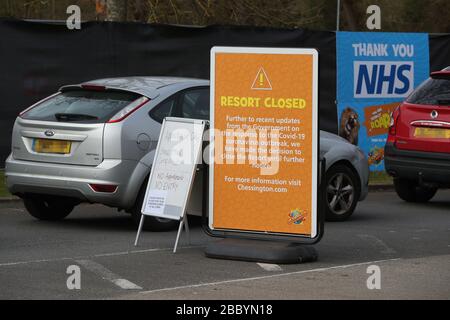 NOTA PER I REDATTORI: TARGA PIXELATED BY PA PICTURE DESK un cartello che dice ai clienti che il parco a tema è chiuso mentre le auto si allineano alle 09.45 in attesa di accedere al sito di test di coronavirus nel parcheggio di Chessington World of Adventures, nella Grande Londra, Mentre il Regno Unito continua a bloccarsi per contribuire a frenare la diffusione del coronavirus. Foto Stock