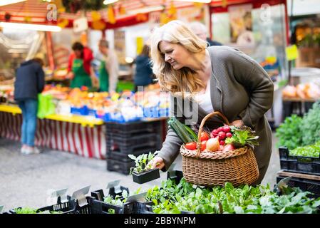 Una donna attraente di mezza età acquista prodotti freschi sul mercato Foto Stock