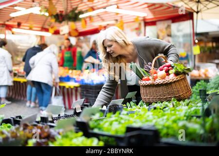 Una donna attraente di mezza età acquista prodotti freschi sul mercato Foto Stock