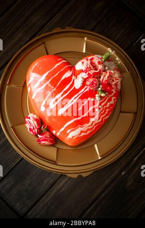 Torta di mousse al cioccolato e alla fragola a forma di cuore rosso con rose. Foto Stock