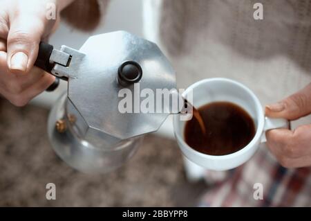 Donna che versava il caffè da un piatto di moka per la colazione al mattino Foto Stock