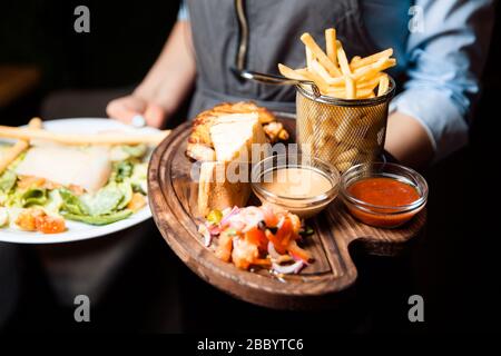 Ali di pollo barbecue con due salse. Servito con patatine fritte, insalata di pomodoro e cipolla e fette croccanti di pane. Foto Stock