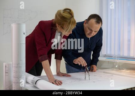 Due Architetti in ufficio alla scrivania che guardano su un progetto. Designer attenti con occhiali pensare e discutere del progetto. Foto Stock