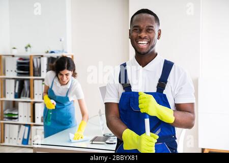 Ritratto di un Janitor felice maschio con apparecchiatura di pulizia in ufficio Foto Stock